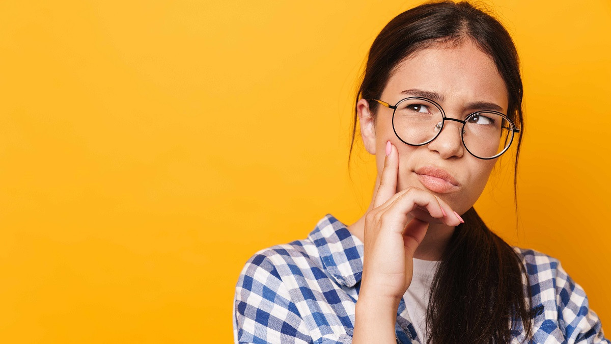 Eine jugendliche Person stützt ihr Kinn in die Hand und blickt nachdenklich